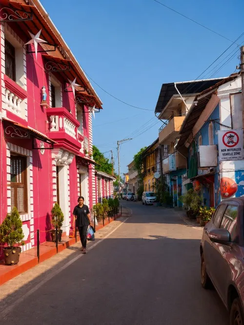 Vibrant yellow and deep blue traditional residential building facades along a narrow street track in Fontainhas.